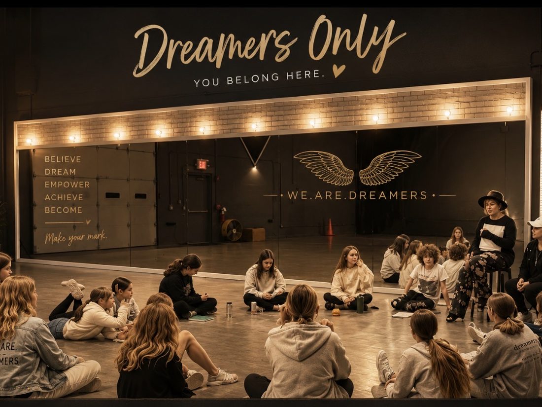Dreamers sitting in a circle on the studio floor beneath the Dreamers Only — You Belong Here wall